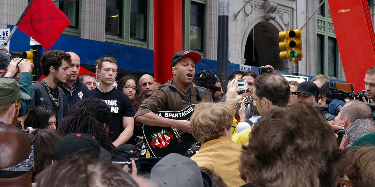 Rage Against the Machine guitarist Tom Morello surrounded by a crowd playing a guitar