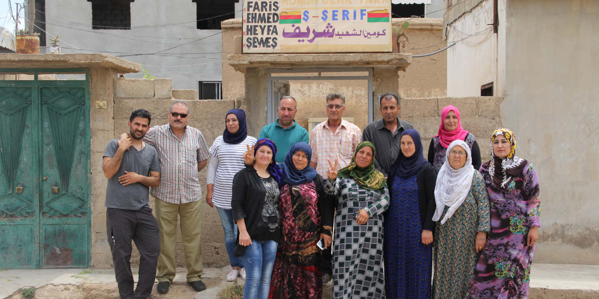 A photo of a group of people taken outside of a Komîngeh, or neighbourhood office