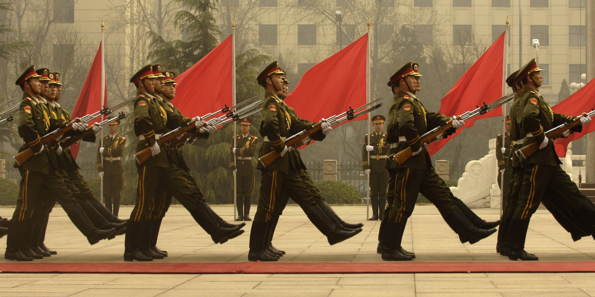 Soldiers of China's Peoples' Liberation Army marching in Beijing bearing red flags