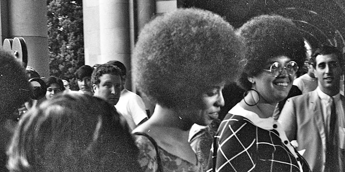 Black and white photograph of Angela Davis walking through crowd