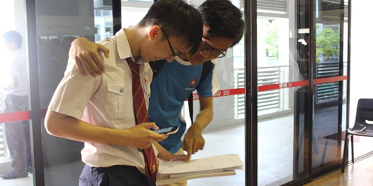 Two students embracing whilst looking at exam results