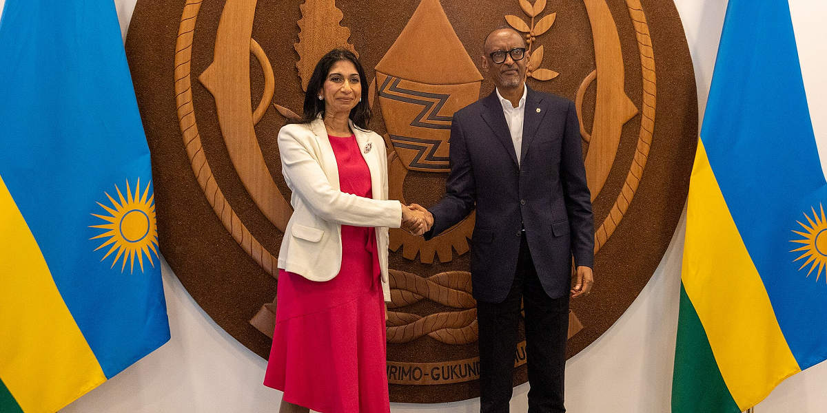 UK Home Secretary Suella Braverman stands shaking the hand of the President of Rwanda, Paul Kagame, in a press photograph, stood in front of the crest and flags of Rwanda