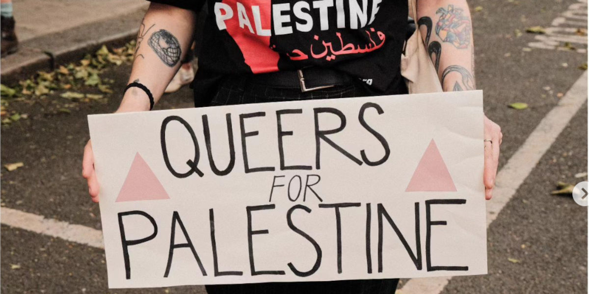A protester in a Palestine t-shirt holds a placard that reads Queers for Palestine