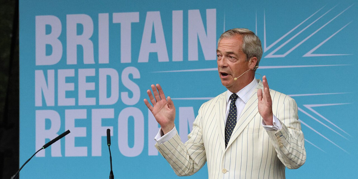 Reform UK leader Nigel Farage speaking at a rally with a backdrop reading 'Britain needs reform'
