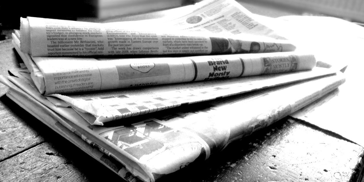 A black and white close up stock photo of a stack of newspapers